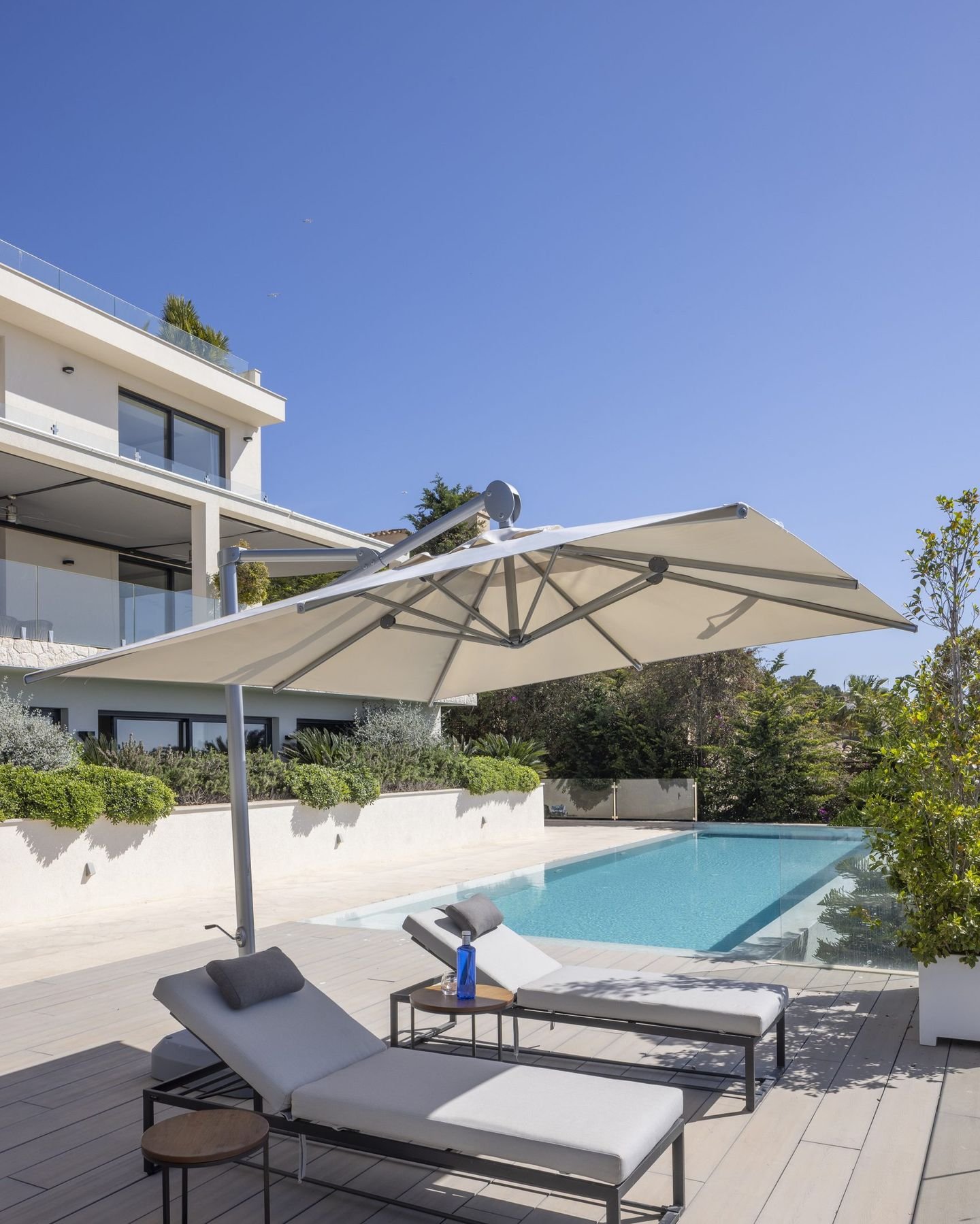 Liegen am Beckenrand eines Pools mit Sonnenschirm