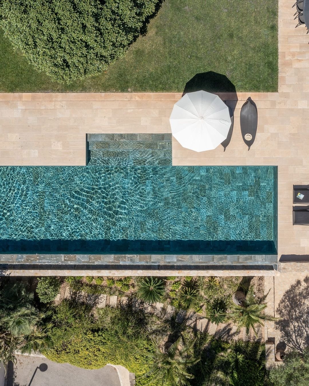 Luftaufnahme eines schmalen Pools zwischen Rasen und Terrasse