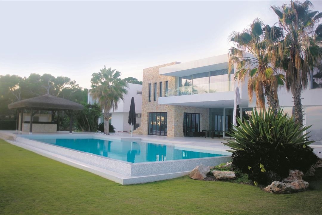 Pool vor einer weißen Villa mit Palmen
