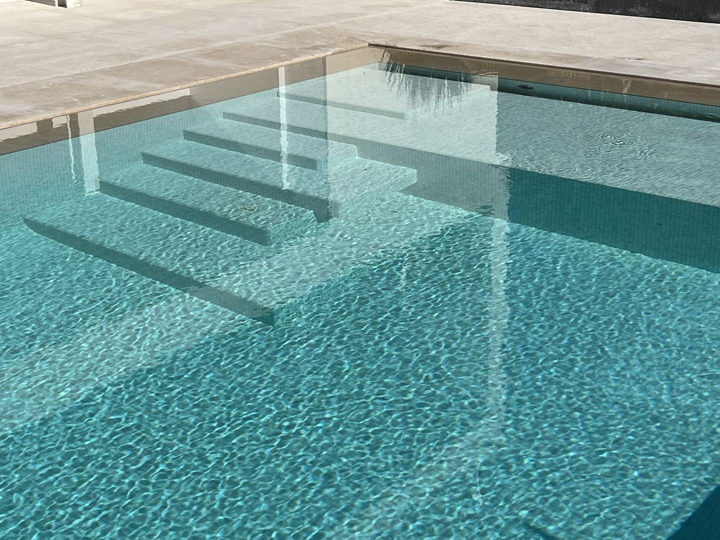 Treppe eines Fliesenpools mit hellblauem Mosaik